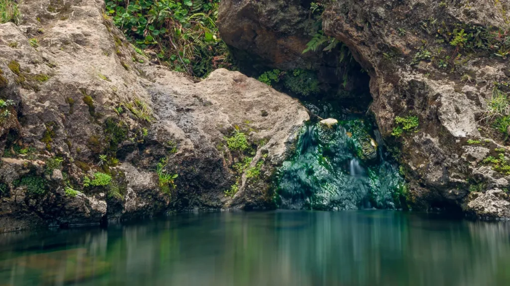 Aguas termales brotando desde una gruta de piedra en las montañas de las Golondrinas, Ecuador